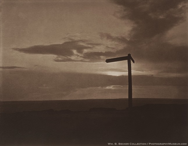 Frank Meadow Sutcliffe, “Quo Vadis?” — a wooden signpost standing alone on an open moor beneath a cloud-filled sky